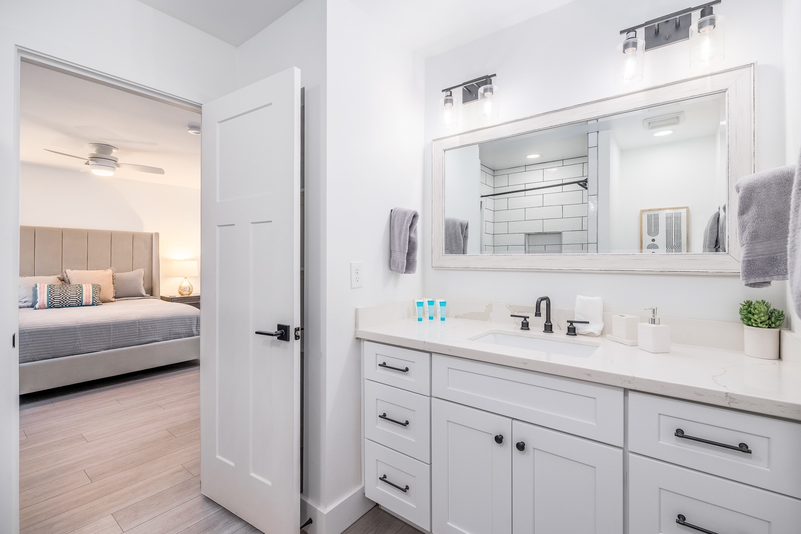 Your private ensuite bathroom features fresh white tile, a spacious vanity, and soft towels, connecting seamlessly to your peaceful bedroom retreat just steps away.