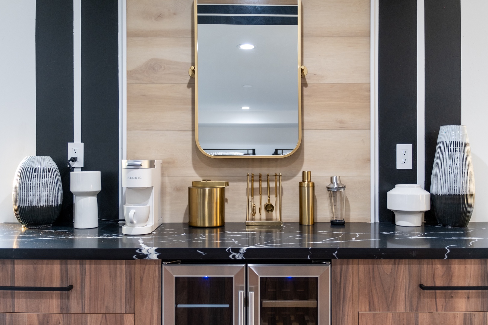 A stylish vanity station awaits, featuring elegant gold accents, a statement mirror, and thoughtful amenities including a coffee maker. The black marble countertop and chic décor create a luxurious morning routine for your stay.