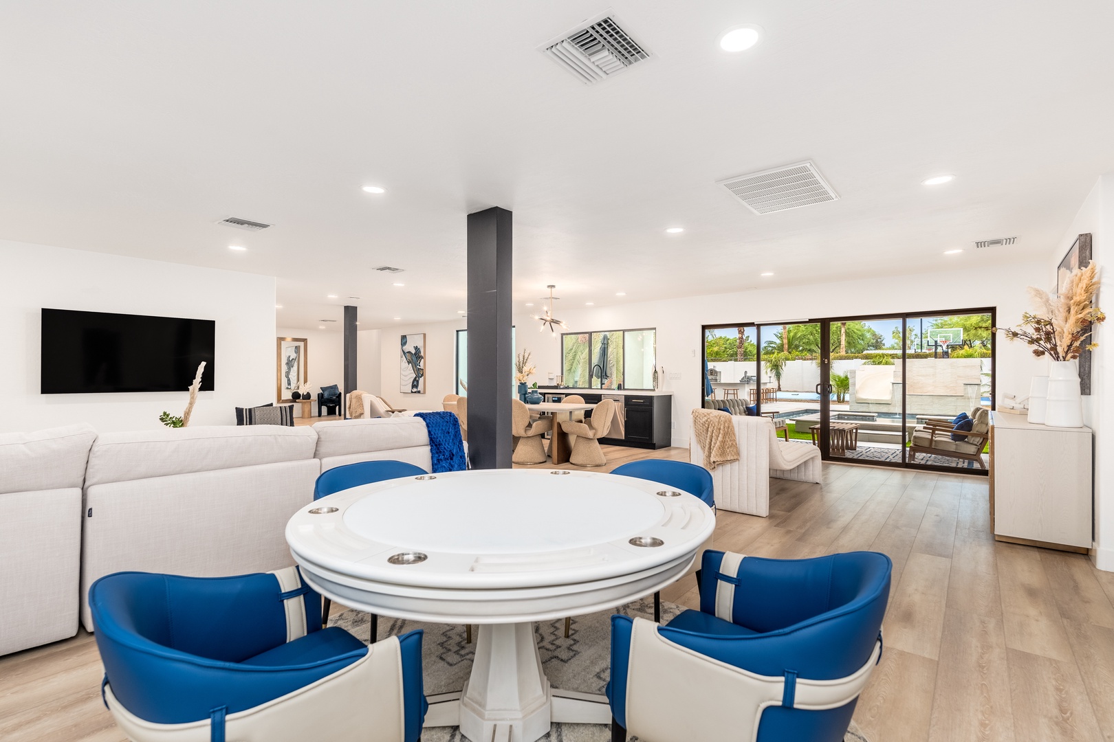 Step into your open-concept paradise where natural light floods through floor-to-ceiling glass doors, revealing a sparkling pool just beyond. Modern elegance meets comfort in this airy living space.