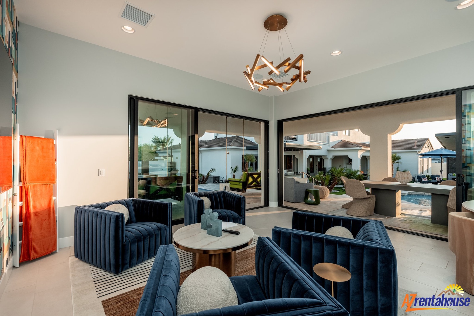 Sink into plush navy velvet seating while enjoying seamless indoor-outdoor flow through floor-to-ceiling windows overlooking your private pool oasis.