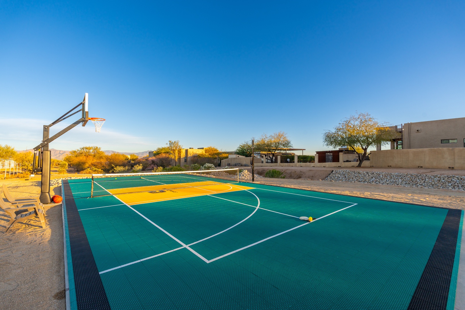 A multi-sport court set against a stunning desert backdrop offers endless possibilities for friendly competition. The clear desert sky and mountain views create an ideal setting for outdoor recreation.