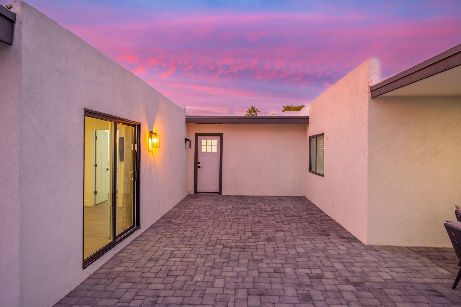 Private courtyard entrance framed by warm adobe walls beneath a stunning desert sky at dusk, offering secure and peaceful arrival.
