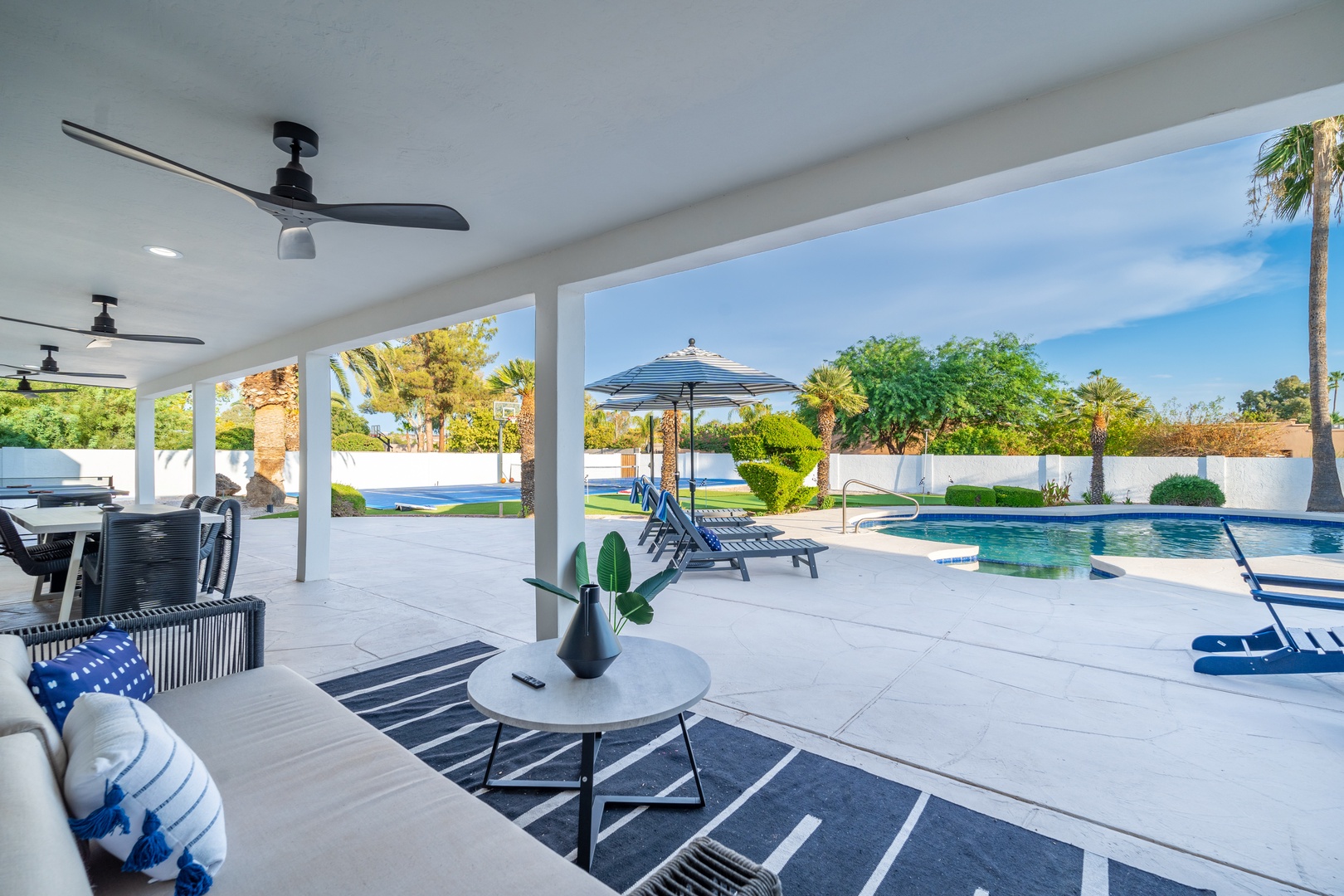 Relax under the covered patio with ceiling fans keeping you cool as you gaze at the sparkling pool framed by lush palms and sunny desert skies.