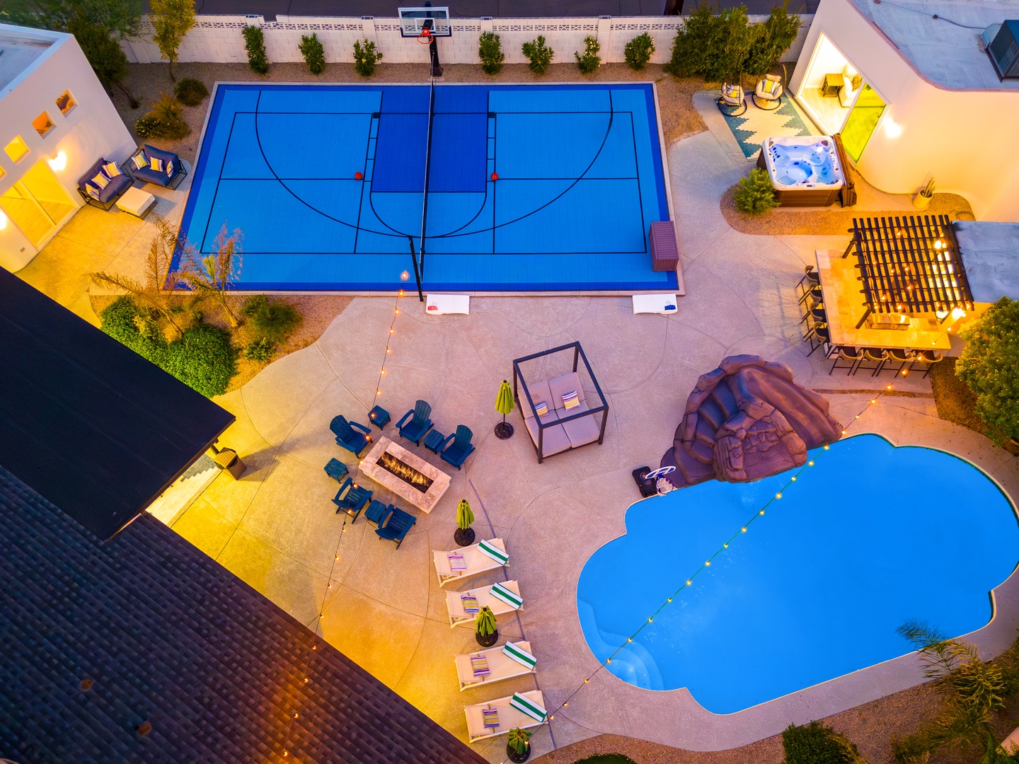 Aerial view showcasing a comprehensive recreation complex with full-sized sport court, resort-style pool, covered dining pavilion, fire pit lounge seating, and multiple relaxation zones—a complete entertainment destination.