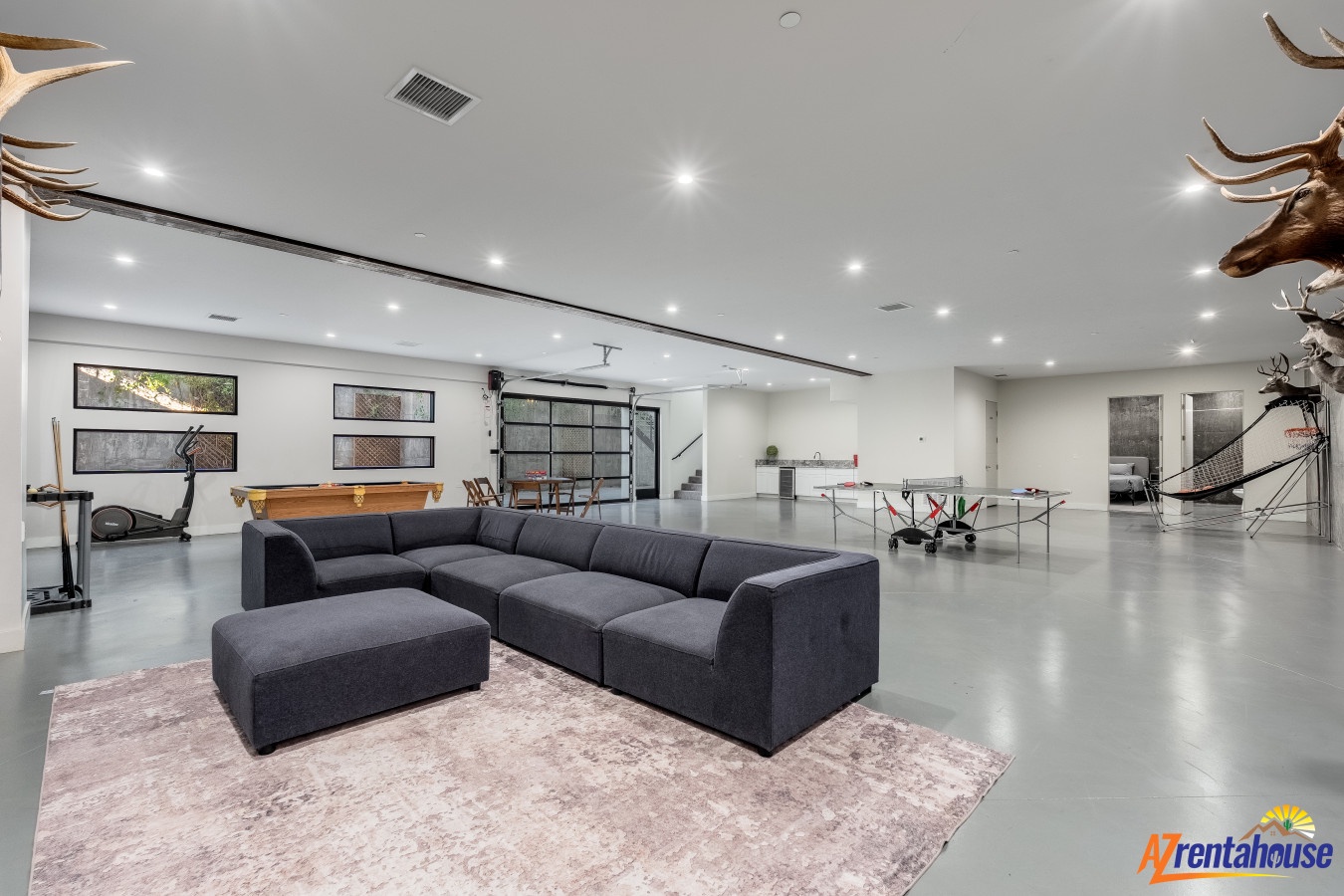 Unwind in this expansive entertainment space featuring modern seating, pool table, and unique decor for your ultimate relaxation.