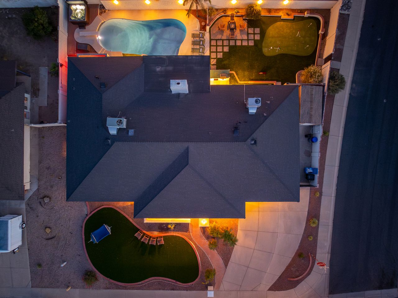 Aerial view of the property showcasing a uniquely curved swimming pool, outdoor hot tub, and surrounding terrace areas with multiple outdoor spaces for relaxation.