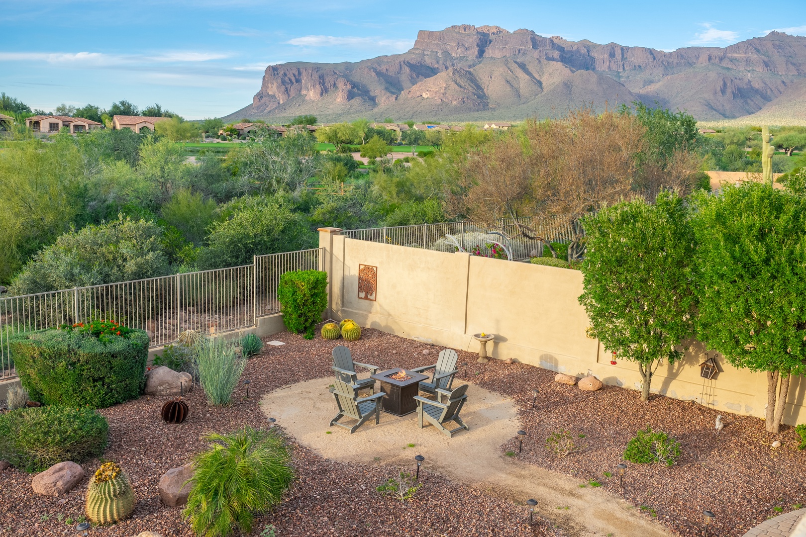The property sits in a desert neighborhood with sweeping mountain views and natural landscape surroundings, featuring a private patio with seating area amidst native landscaping.