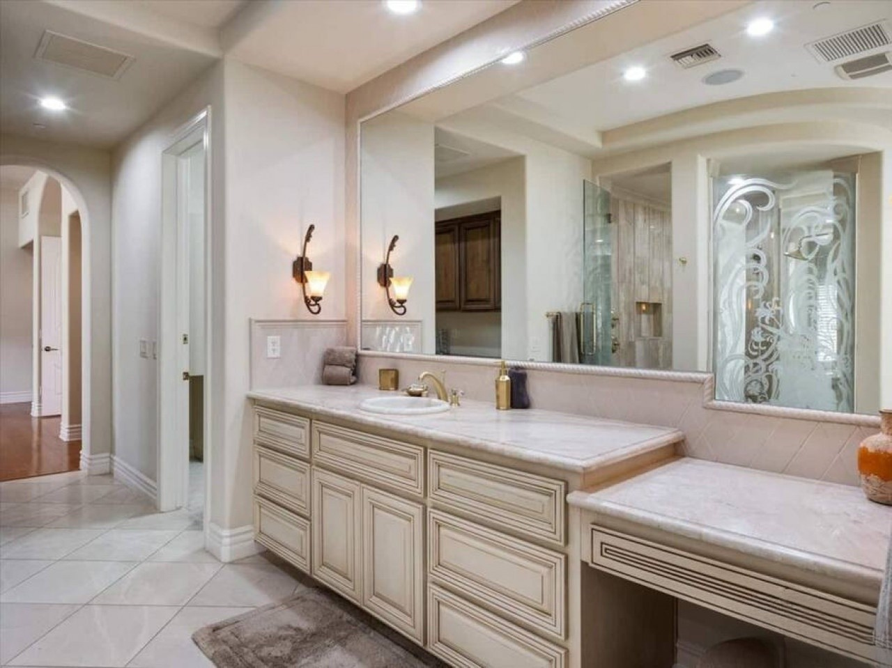 Your spacious master bath features elegant marble counters, ornate frosted glass shower doors, and warm sconce lighting that creates a serene, spa-like retreat for unwinding after a day of adventure.