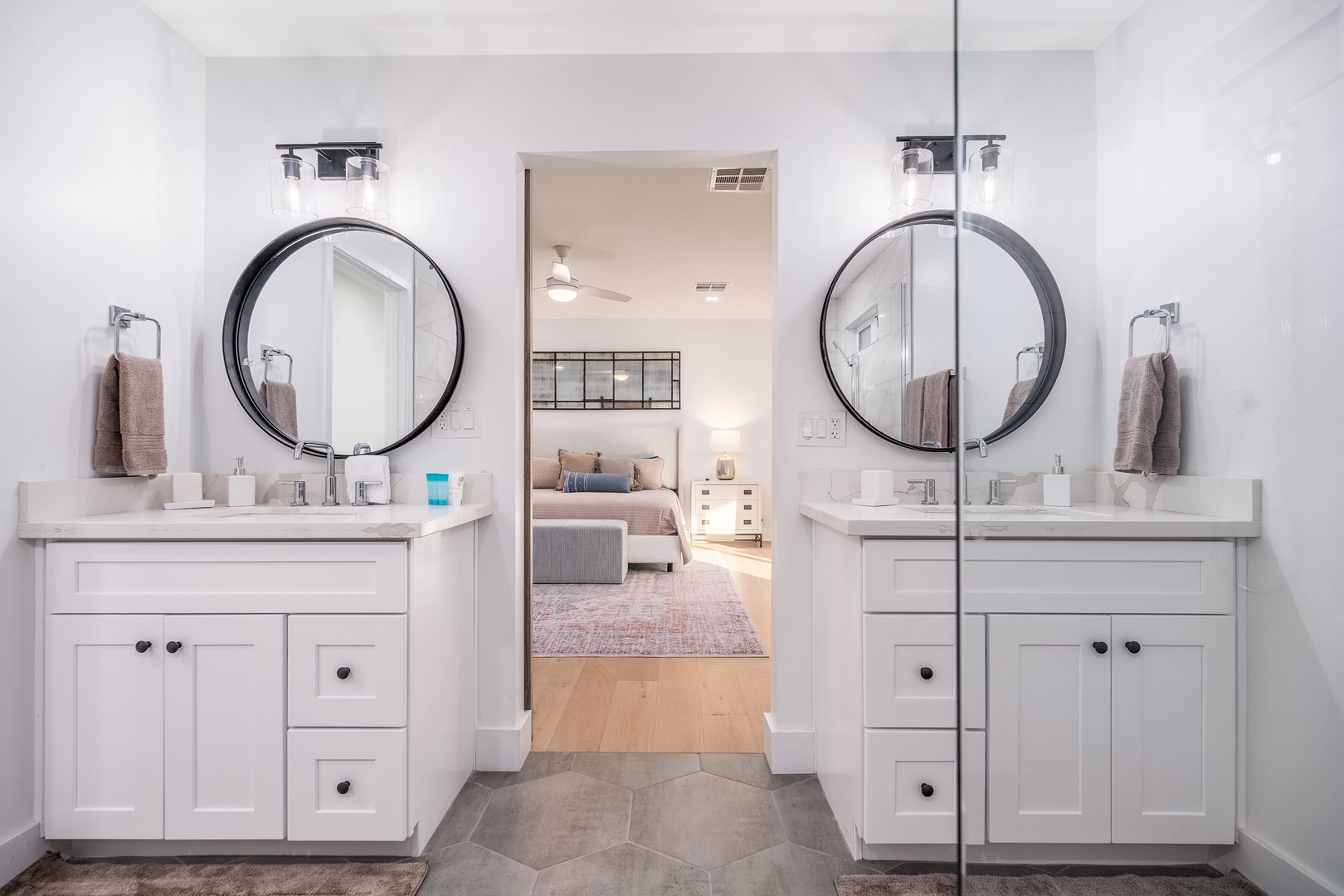 Your bright, elegant bathroom features dual vanities with stylish round mirrors, perfect for getting ready together, and opens right into your restful bedroom—a seamless, inviting space for your stay.