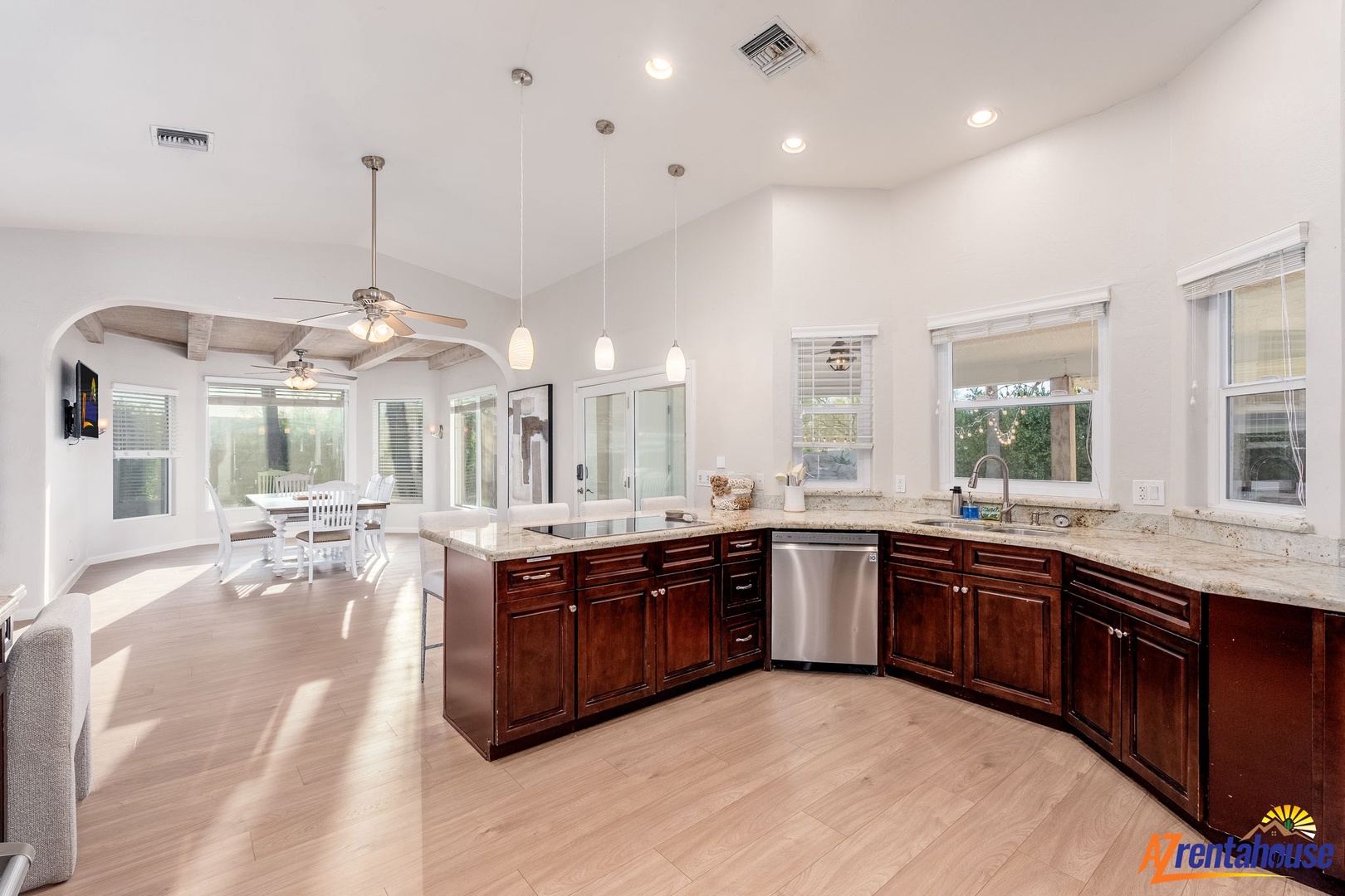 Imagine preparing your favorite meals in this bright, open kitchen with elegant granite countertops, rich wood cabinetry, and stainless appliances—all bathed in natural light from the windows overlooking the dining area where you'll gather.
