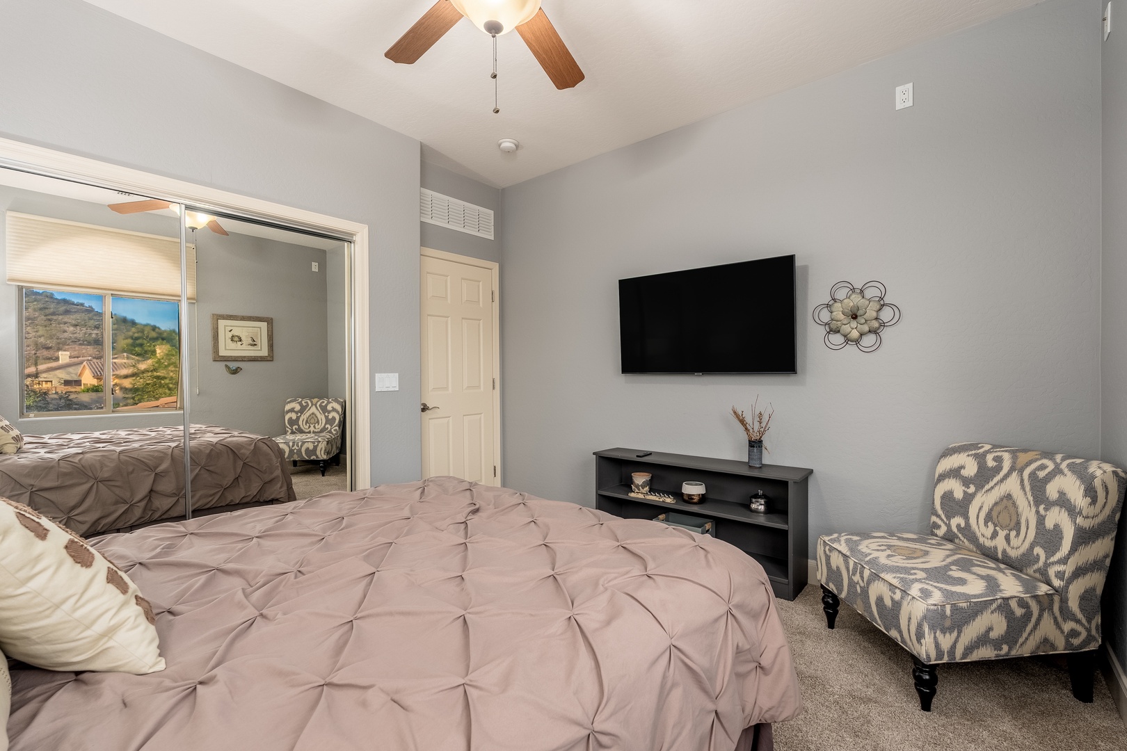 Unwind in your spacious bedroom with soothing colors, a plush bed with elegant pin-tuck bedding, and a mounted TV for your favorite shows. The ceiling fan keeps you cool while the mirrored closet doors add light and openness to your private retreat.