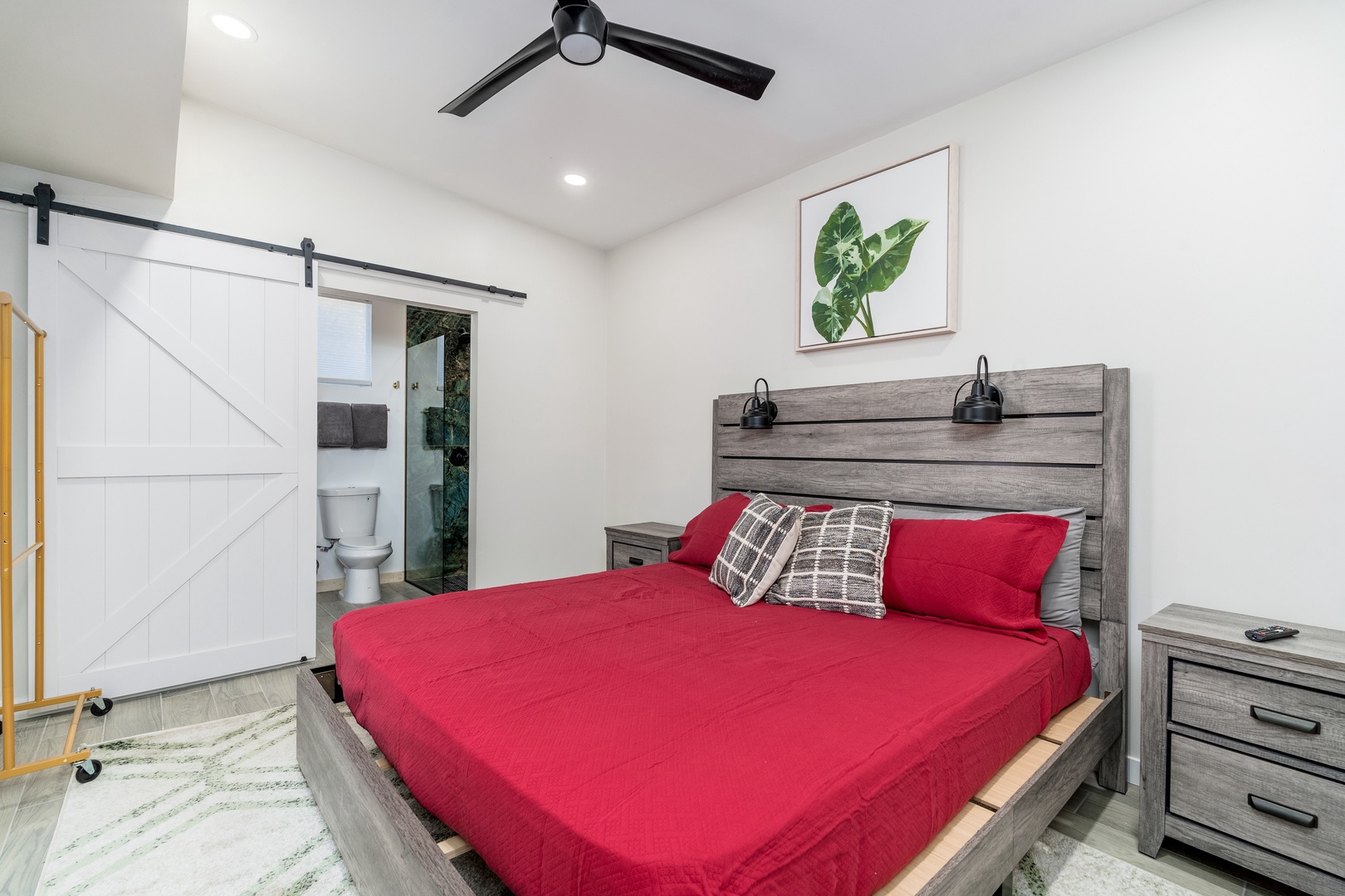 Relax in your cozy bedroom with a queen bed, modern ceiling fan, and charming barn door leading to your private en-suite bathroom.