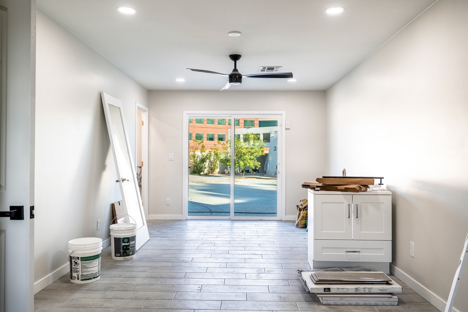Step into this bright, open space featuring clean lines, durable tile flooring, and a ceiling fan to keep you comfortable. Large glass doors welcome natural light throughout.