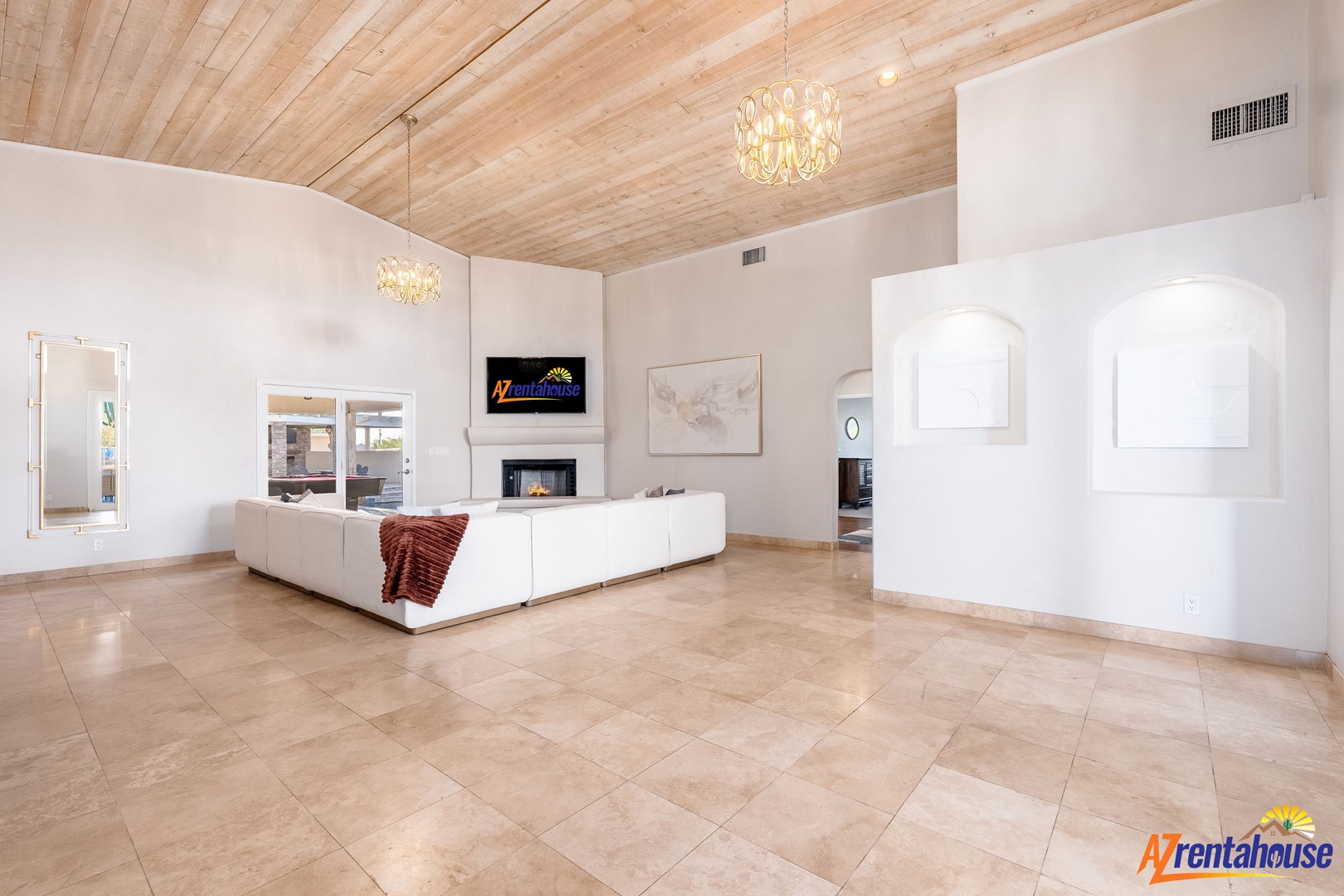Relax in your spacious living area featuring vaulted wood ceilings, elegant lighting, and a cozy fireplace—perfect for unwinding after desert adventures.