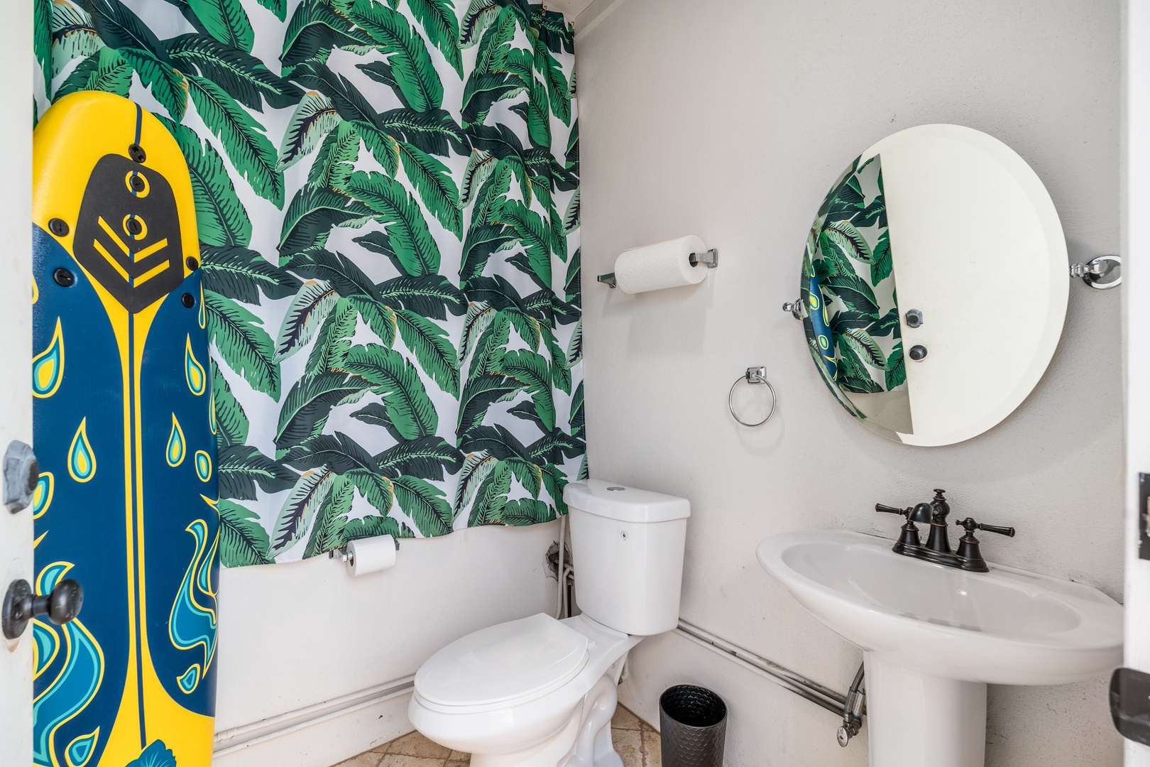Bright tropical vibes welcome you into this refreshing bathroom, where bold palm leaf prints and creative coastal touches set a playful, breezy mood for your stay.