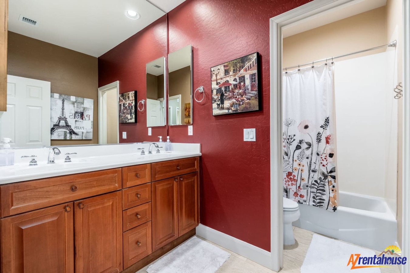 Refresh in your thoughtfully designed bathroom with rich red accent walls, dual vanities, and artwork creating a welcoming retreat.