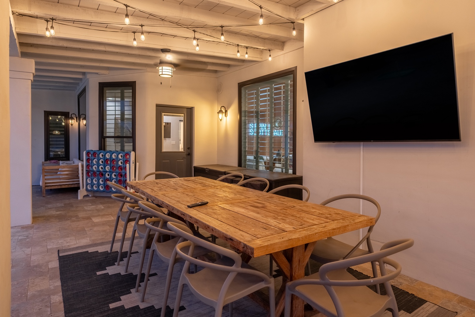 Gather around this inviting dining table with exposed beams above and string lights creating a warm glow for your group meals and game nights together.