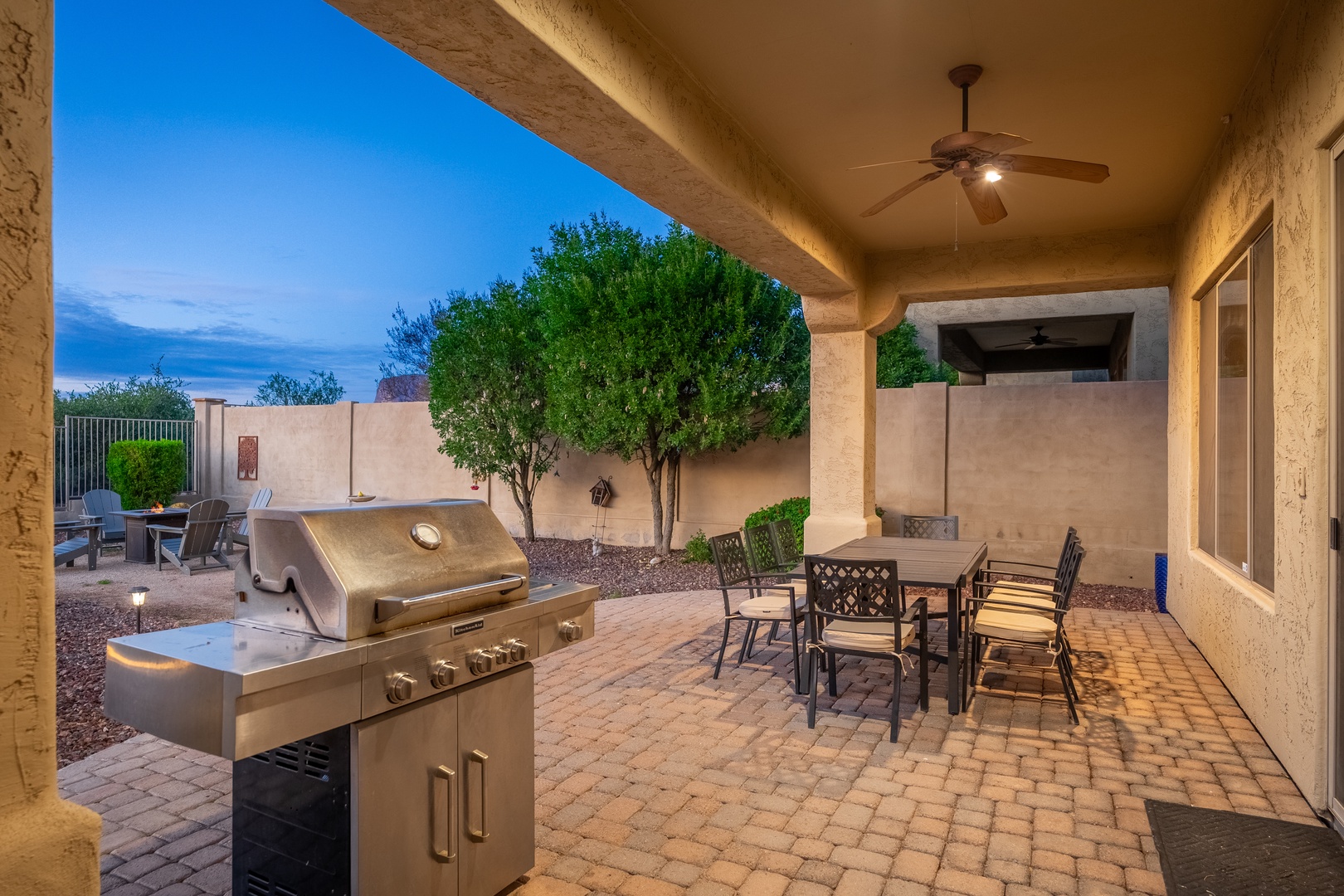 Covered patio with built-in BBQ grill, dining table, and evening lighting creates your perfect Arizona outdoor living and entertainment space.