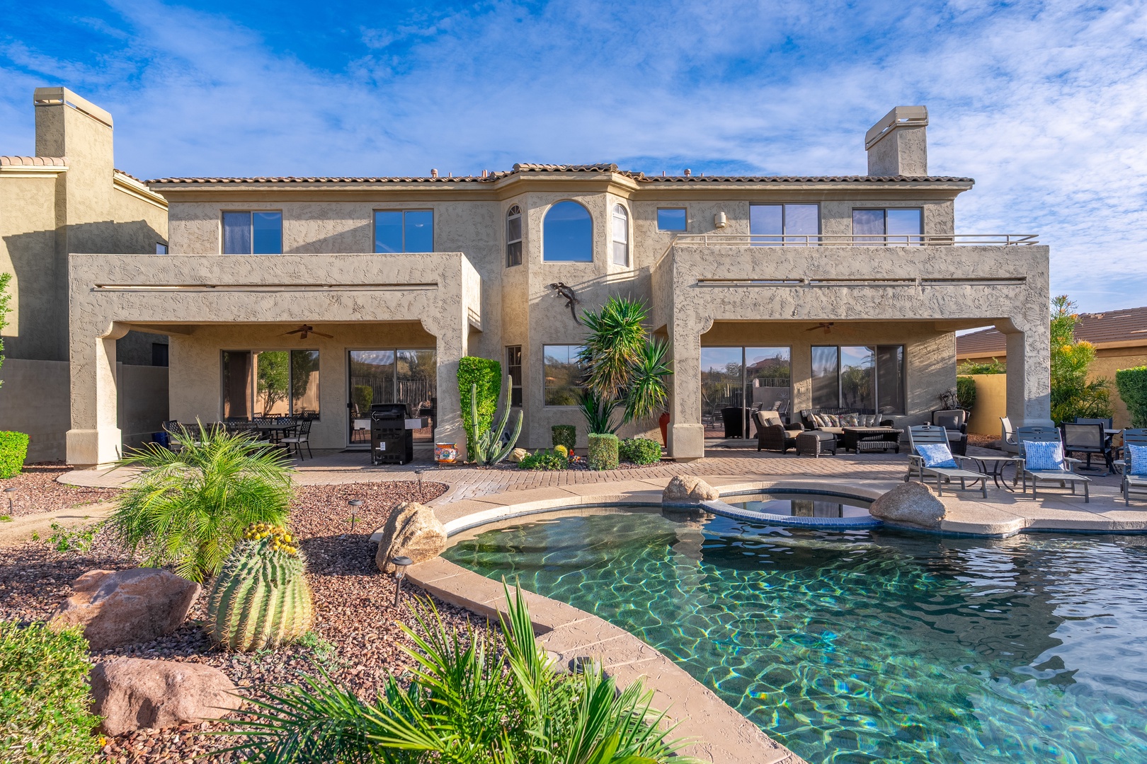 A stunning desert estate with a sparkling pool, covered patios, and mountain views. The lush landscaping and inviting outdoor lounge areas create a perfect retreat under endless Arizona skies.