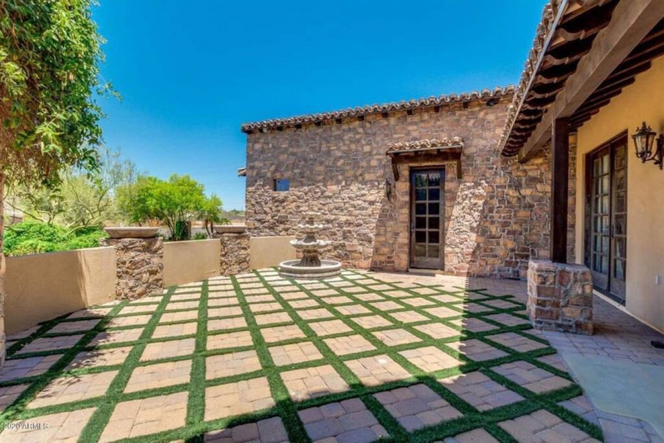 Stone-walled courtyard with fountain centerpiece and geometric paver design creates a tranquil outdoor retreat.