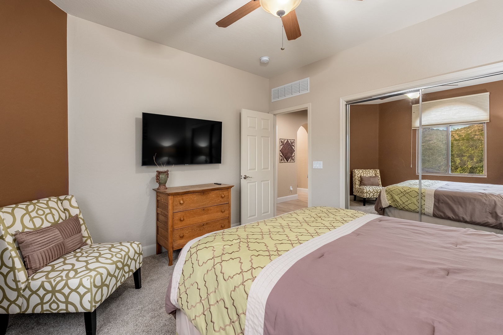 Unwind in your serene retreat with a plush bed, cozy seating, and entertainment at your fingertips. Natural light and a ceiling fan create a peaceful atmosphere for restful nights.