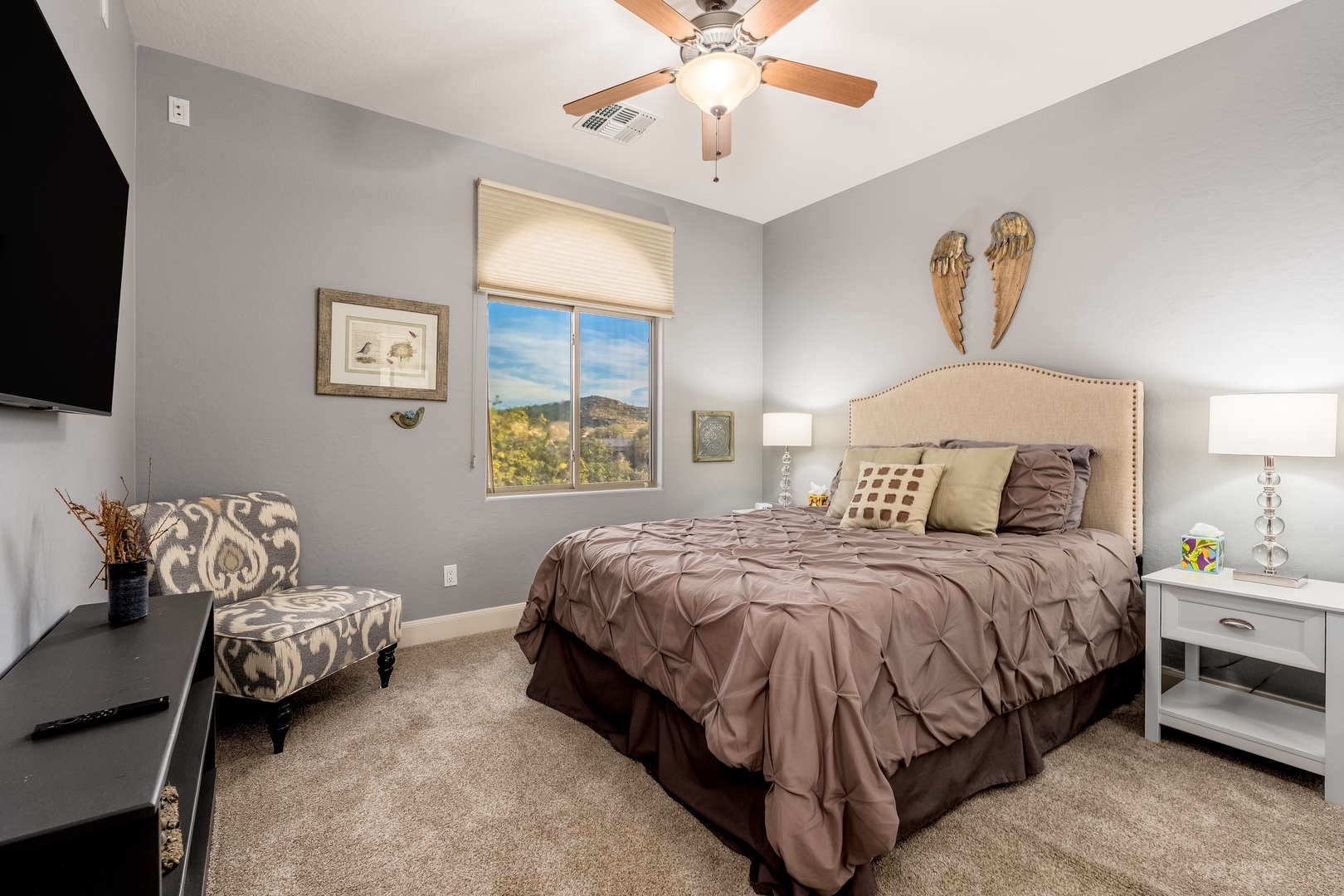 Wake up in your restful bedroom with serene gray walls, a cozy bed adorned with elegant linens, and a ceiling fan overhead to keep you comfortable year-round.