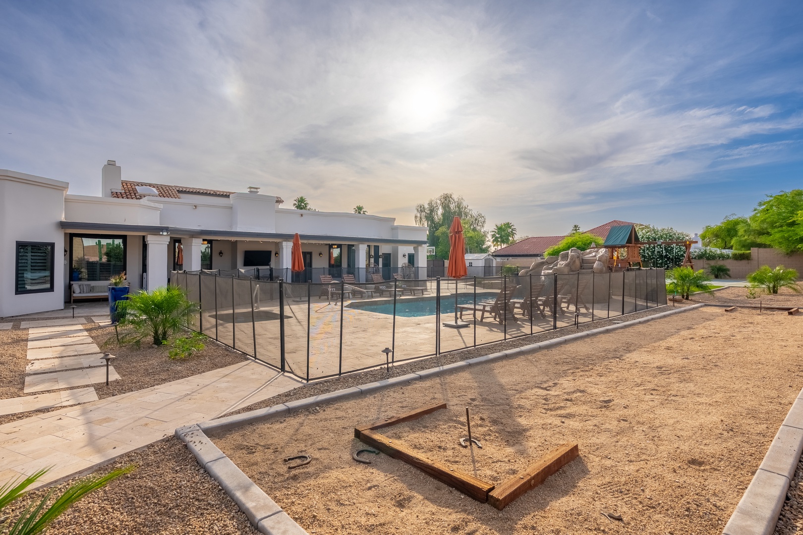 Modern desert retreat with a refreshing pool, shaded lounge seating, and a fun game area set against mountain views and open sky—perfect for sunny days and clear evenings.