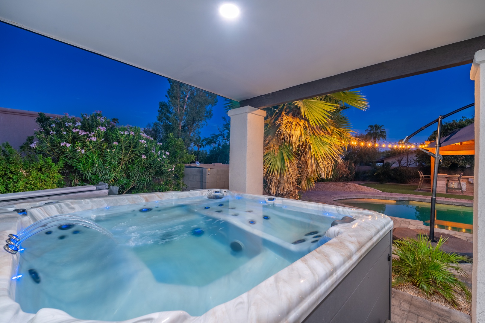 Sink into the bubbling hot tub as twilight settles, surrounded by tropical palms and a glowing pool just steps away—your private oasis awaits.