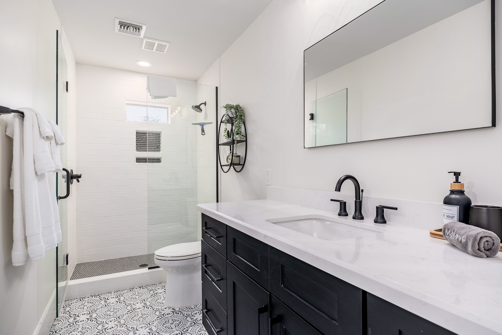 Refresh in your spacious private bathroom featuring modern fixtures, a sleek walk-in shower, stylish patterned floors, and plush towels ready for your arrival.