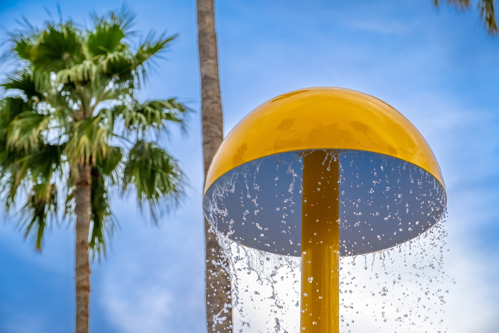 A vibrant yellow water feature provides refreshing fun beneath swaying palms and bright blue skies, part of the property's aquatic recreation area.