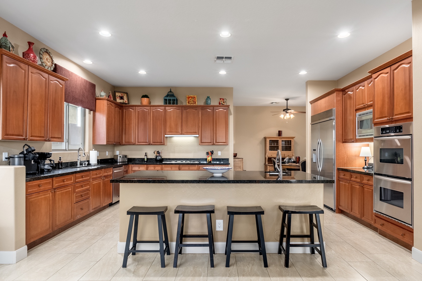 Gather around the spacious island with gleaming granite countertops in this fully-equipped kitchen, where rich wood cabinetry, stainless steel appliances, and ample prep space make cooking feel effortless.