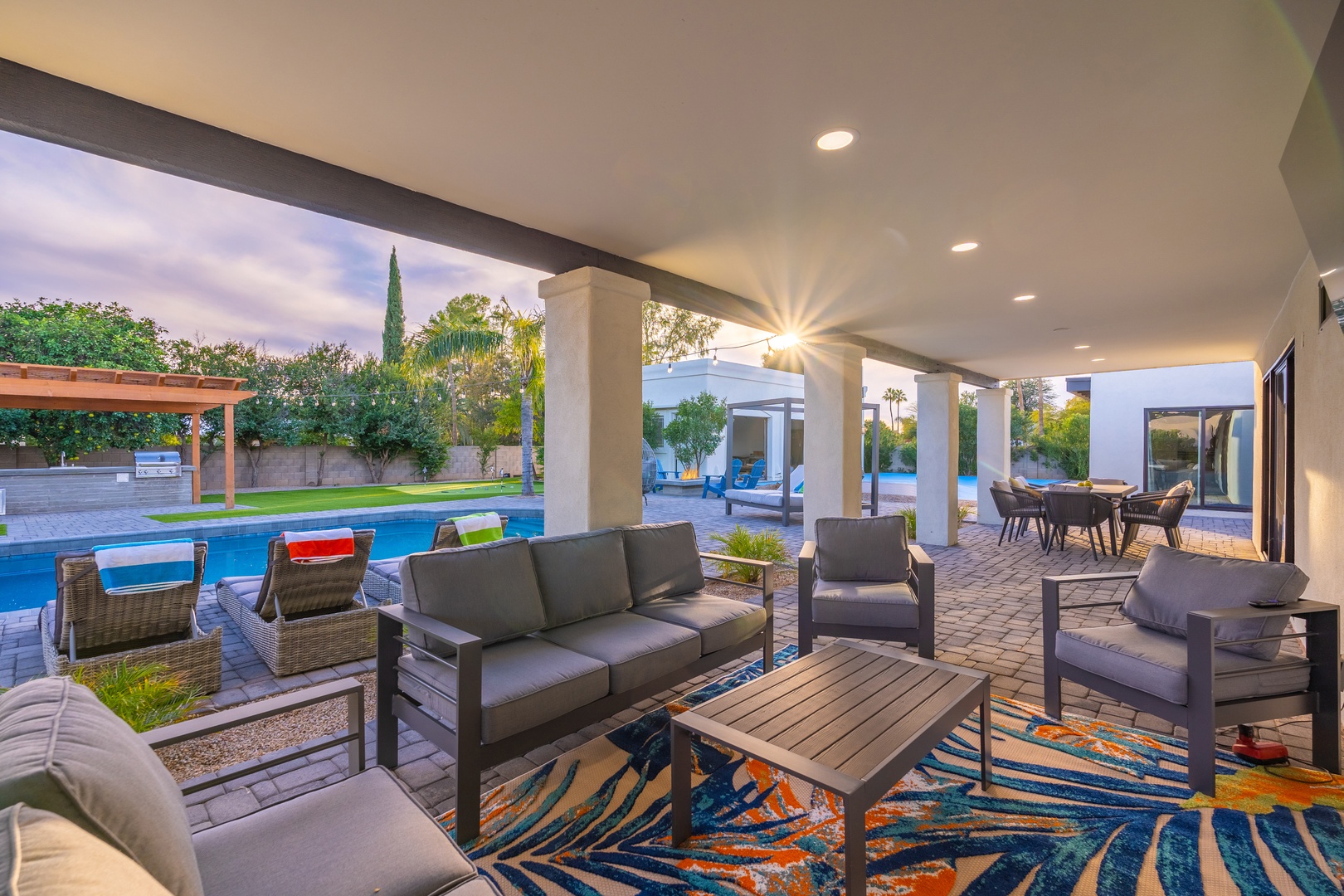 Unwind in your covered outdoor living room, where stylish seating and vibrant decor frame sweeping views of the sparkling pool and lush backyard oasis.