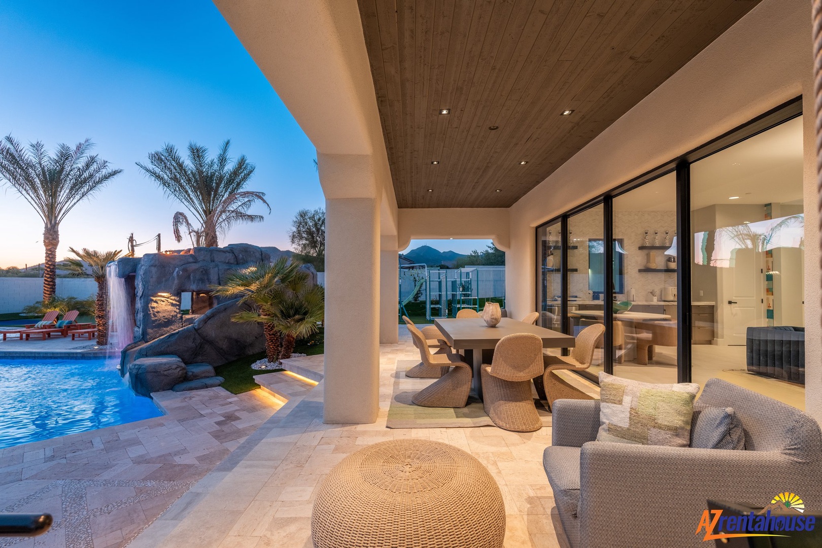 Your covered patio offers seamless indoor-outdoor living with elegant dining space overlooking the shimmering pool and desert landscape beyond.