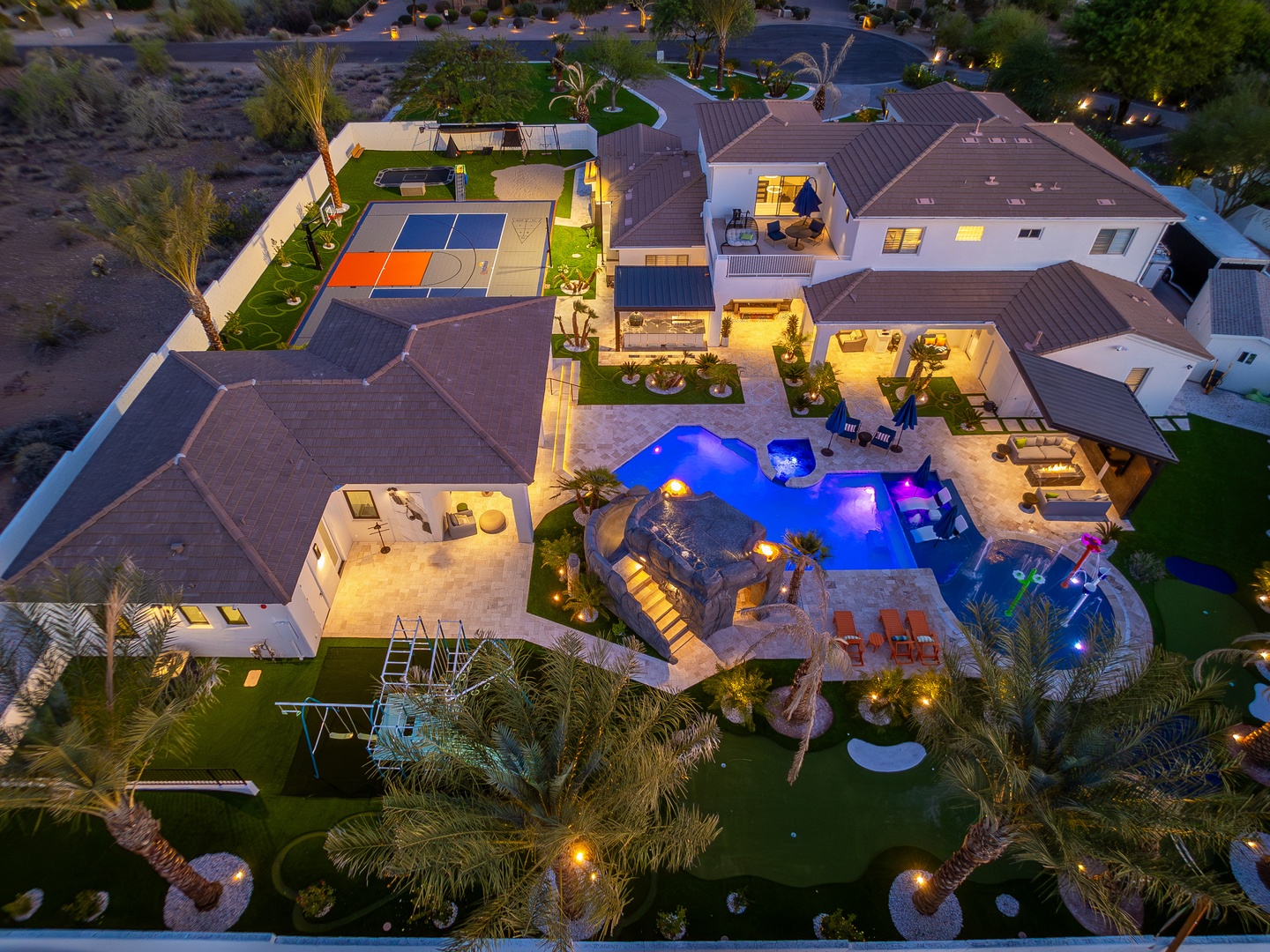 Aerial view of this stunning property showcasing a resort-style pool with spa, basketball court, lush landscaping, and multiple outdoor entertaining areas in a peaceful desert neighborhood setting.