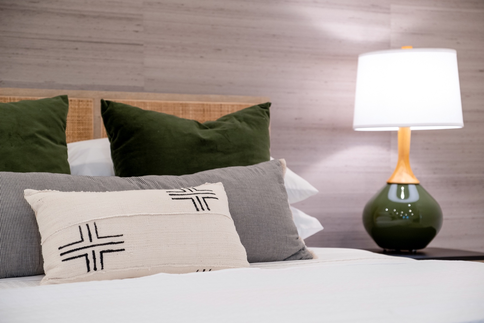 Sink into crisp white linens and a layered mix of pillows. The bedside lamp adds a warm glow, creating your perfect nightly retreat.