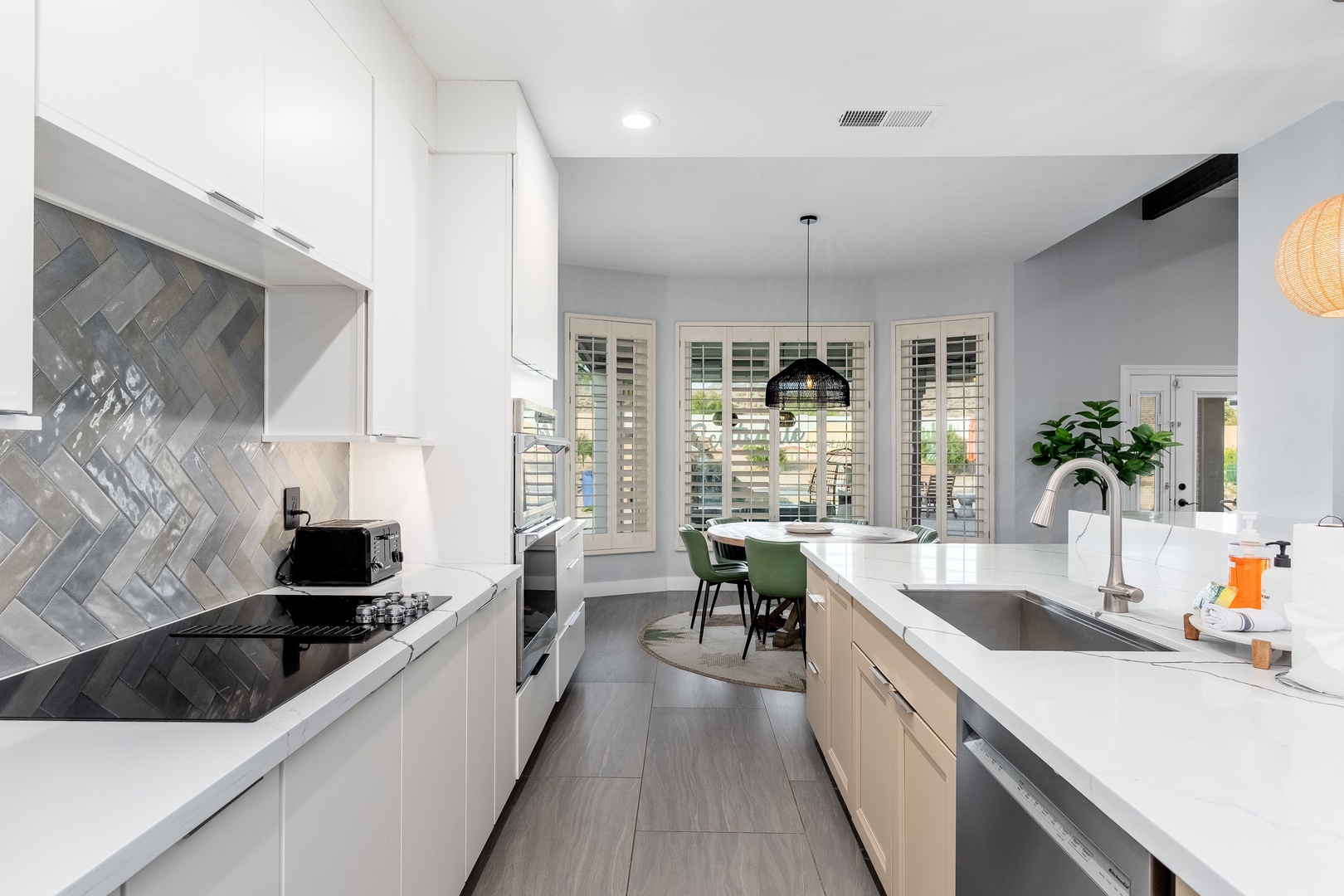 Your gourmet kitchen features modern appliances, sleek white cabinetry, and a stunning herringbone tile backsplash. Natural light floods in through plantation shutters as you prepare meals on quartz countertops.