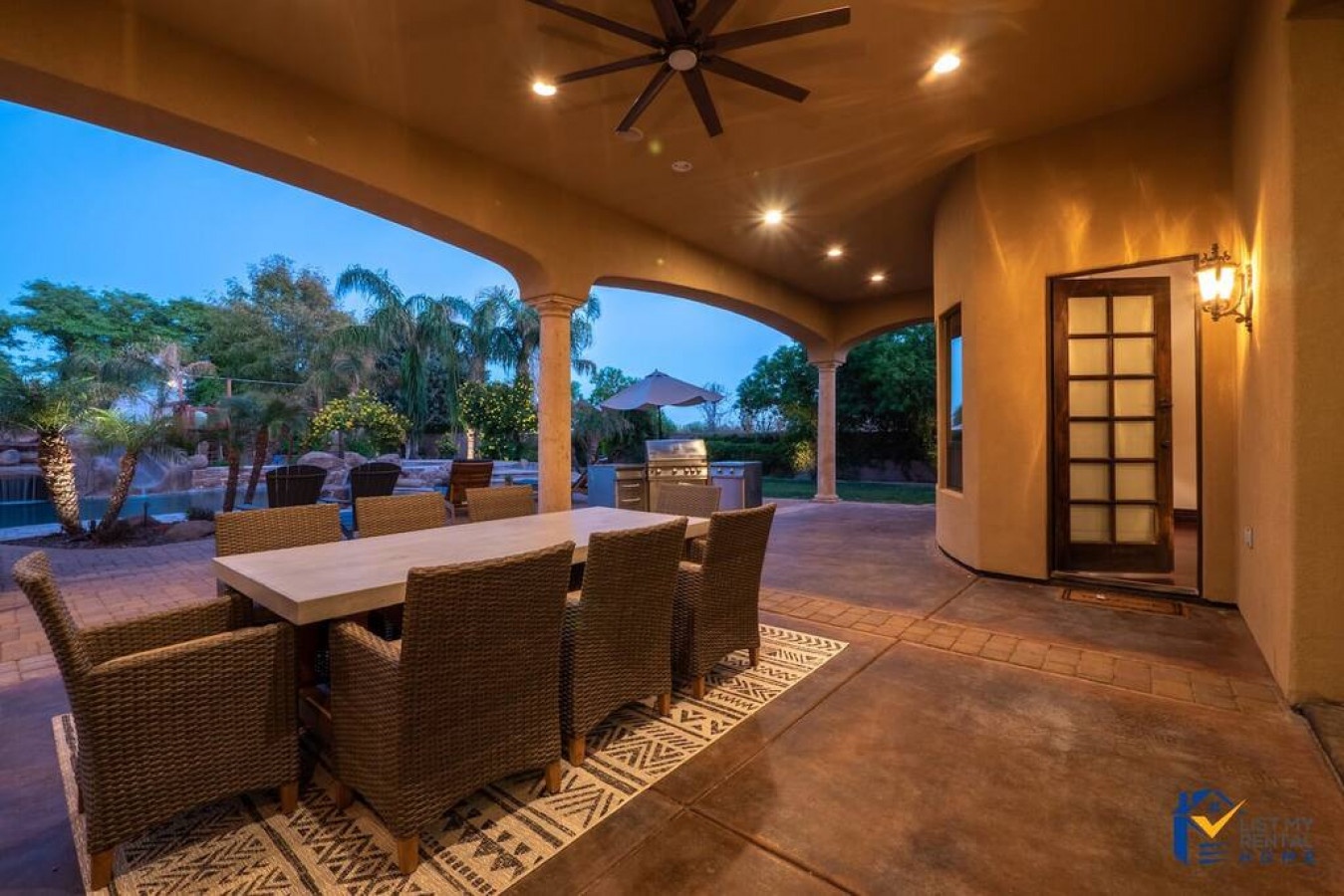Your elegant covered patio features comfortable dining for eight beneath soaring ceilings and warm lighting, perfect for memorable evening meals.