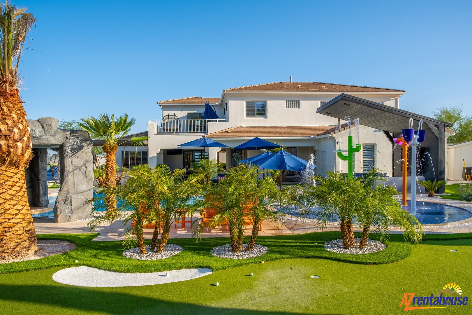 Modern luxury villa featuring an expansive outdoor retreat with swimming pool, children's water play area, and tropical landscaping.