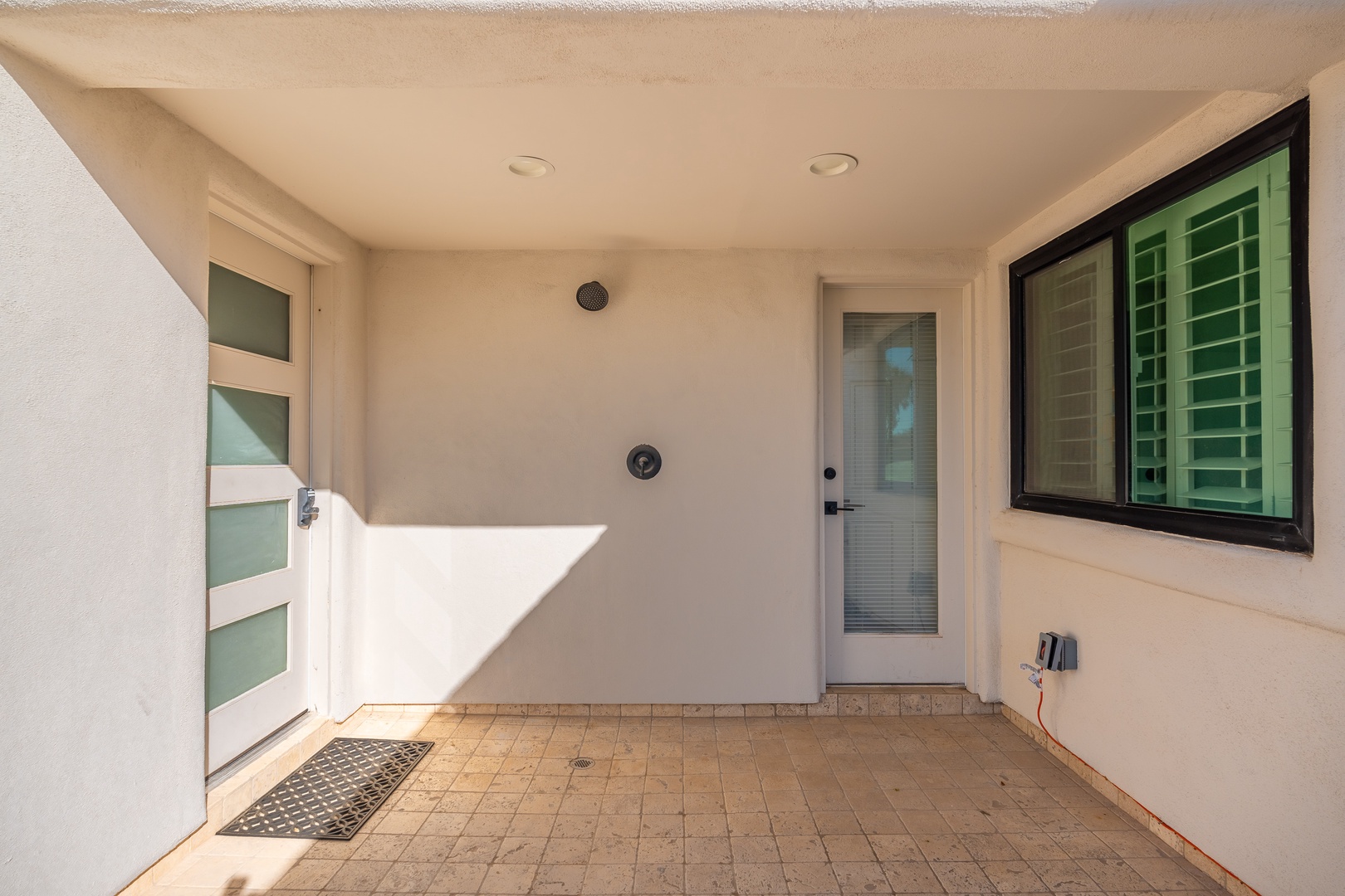A private entrance with modern glass doors and coastal sunlight creates a welcoming arrival point for your beachside retreat.