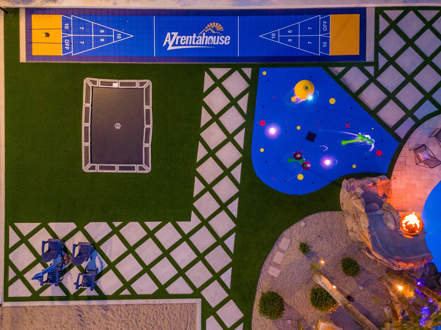Aerial overview of the property showing its distinct outdoor recreational zones including a shuffleboard court, trampoline area, pool with slide, and thoughtfully landscaped grounds—all part of this vacation rental's amenities.