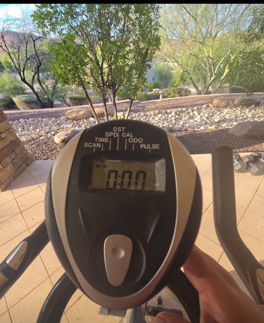 Stay active on the patio with exercise equipment overlooking a peaceful desert landscape and mature trees.
