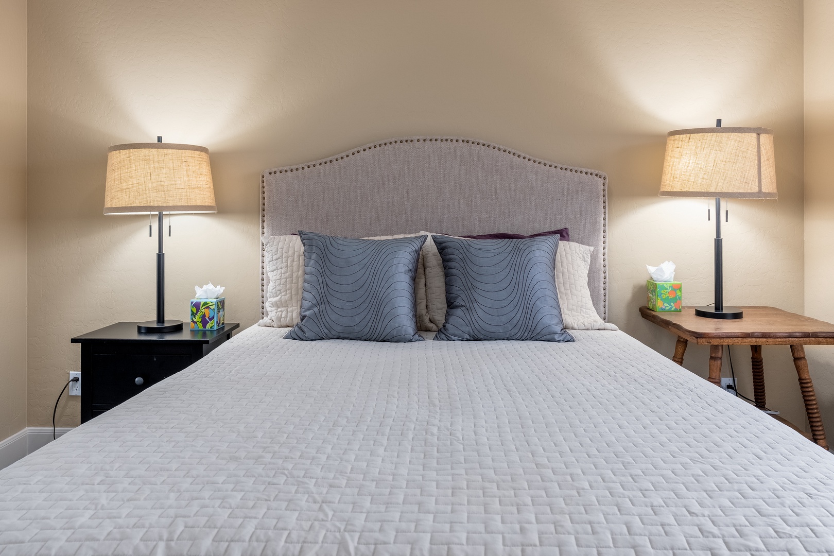 Sink into your plush quilted bed beneath the warm glow of elegant bedside lamps, where thoughtful touches and coastal-inspired accents create your perfect retreat.