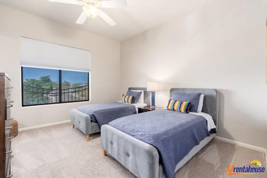 Unwind in your bright twin bedroom featuring plush grey beds and a peaceful view of lush greenery outside your window.