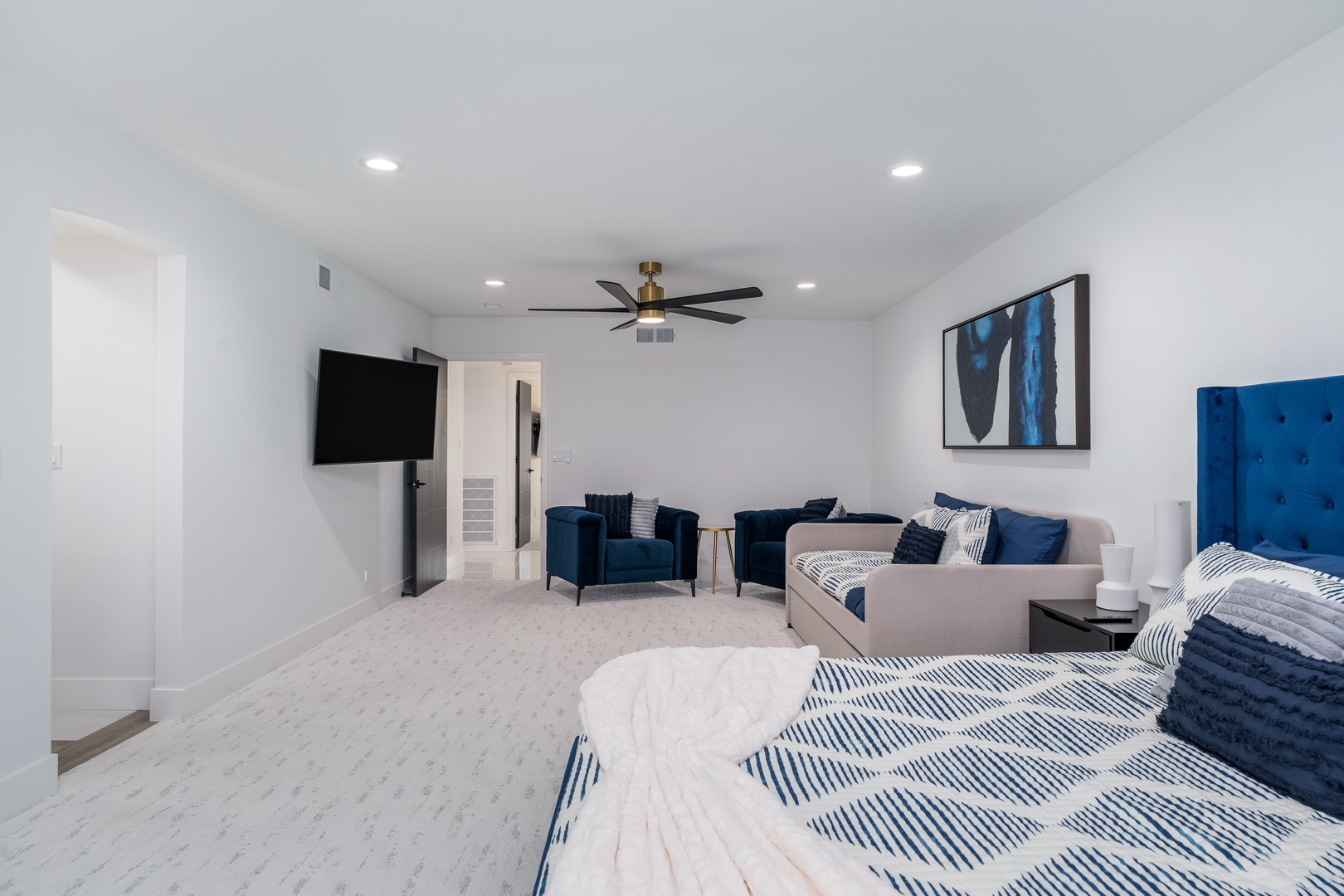 Relax in your spacious bedroom with plush seating and a mounted TV. Crisp linens, modern navy accents, and a ceiling fan create the perfect retreat after a day of adventure.