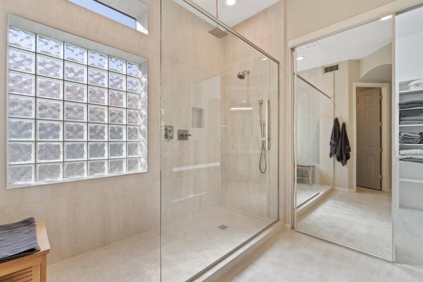 Step into your spa-like bathroom featuring a spacious glass shower with rainfall head and elegant glass block window for natural light.