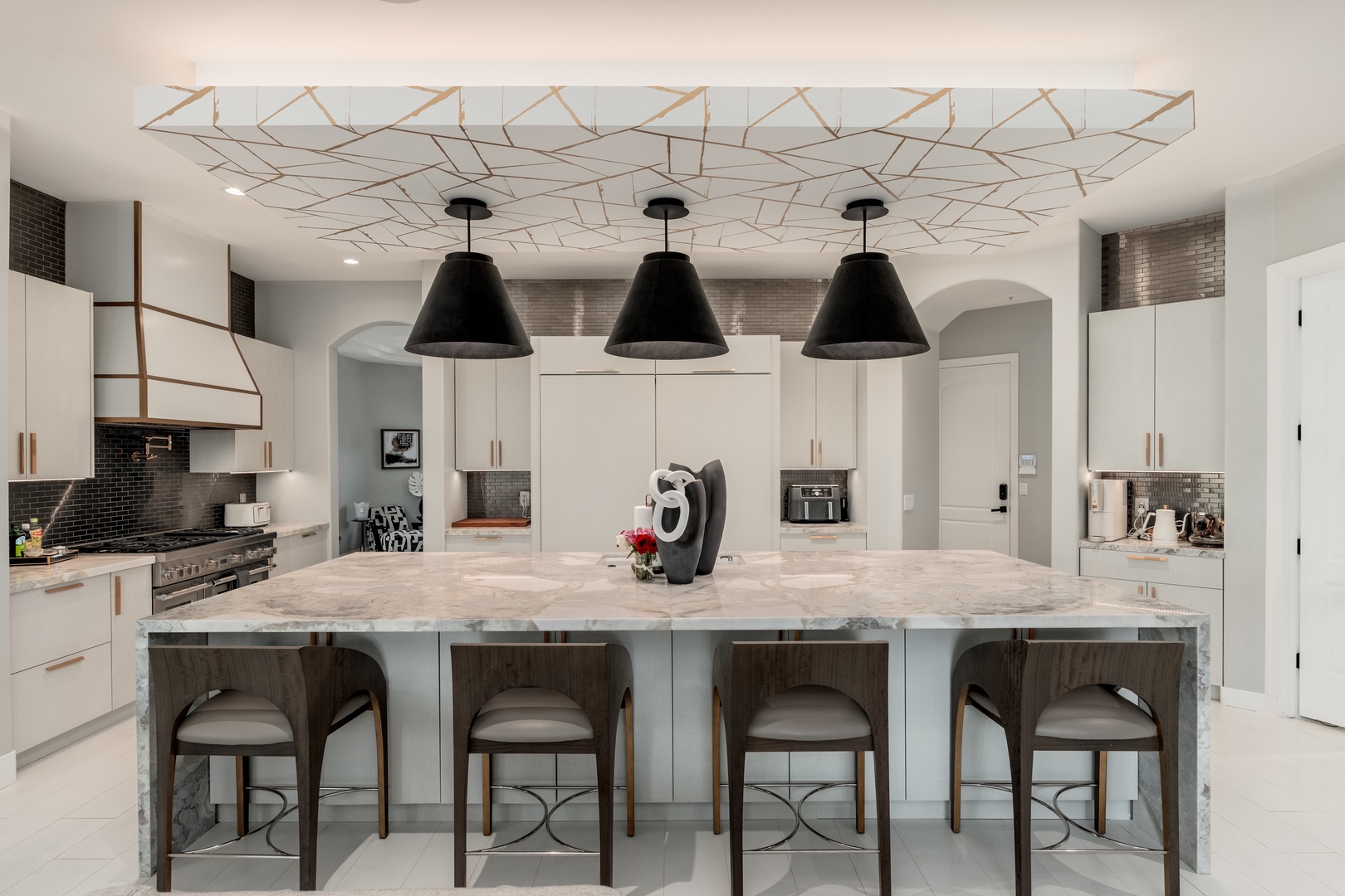 Gather around your stunning marble island beneath elegant pendant lights, perfect for morning coffee or evening conversation in this beautifully designed chef's kitchen.