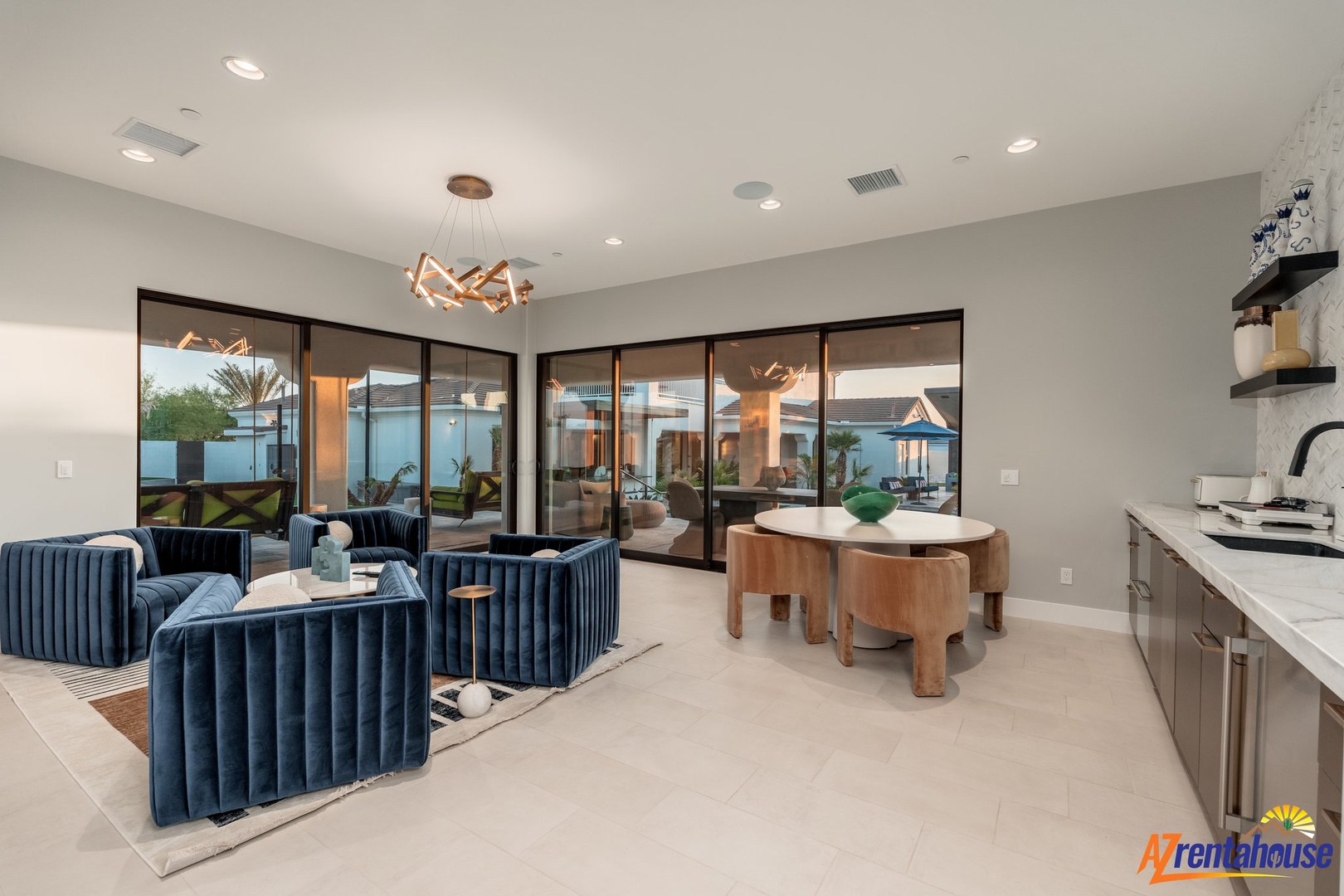 Unwind in your stylish living space where plush velvet seating meets sleek design, with stunning pool views through floor-to-ceiling windows.