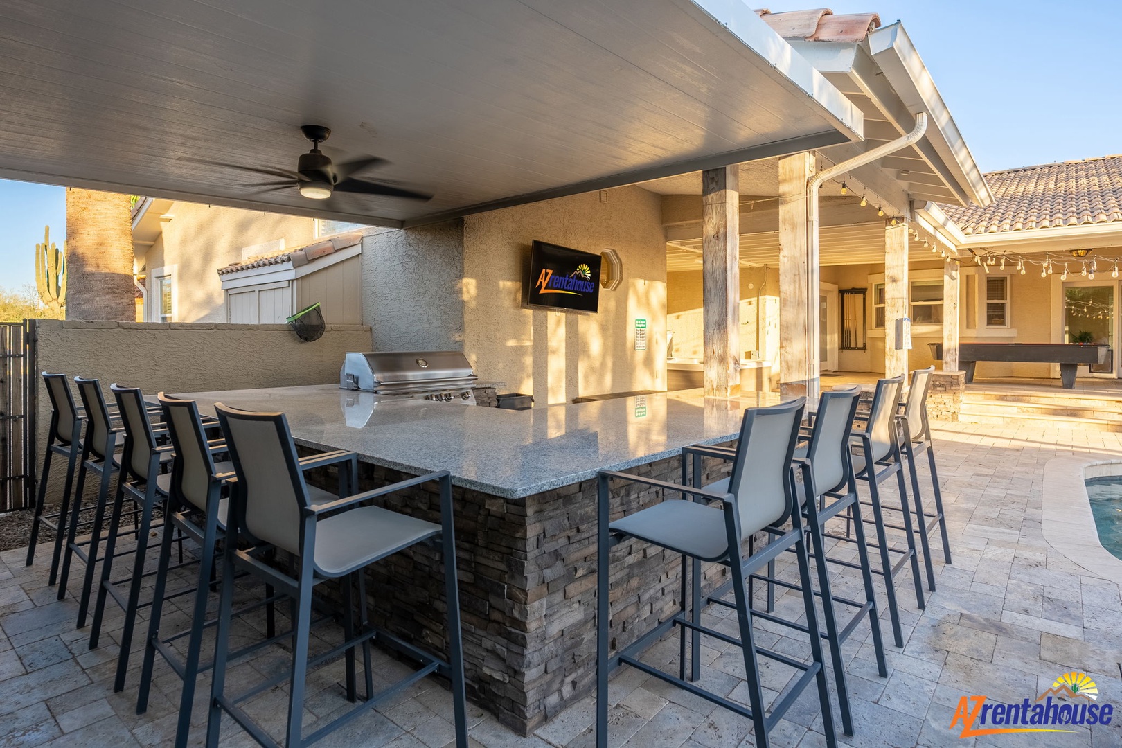 Gather around this covered outdoor bar with counter seating for the whole group, complete with built-in grill and TV—your perfect spot for sunset cocktails and al fresco dining.