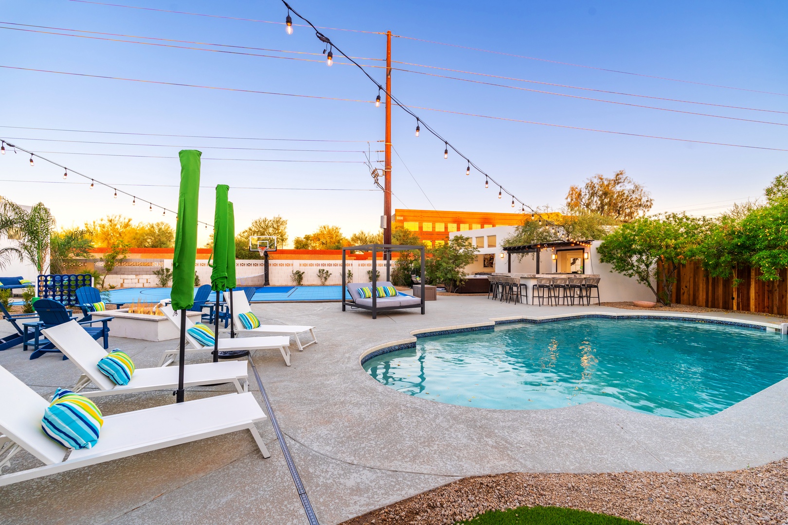 A resort-style backyard oasis offering pool, loungers, dining bar, and string-lit ambiance for unforgettable gatherings under open skies.