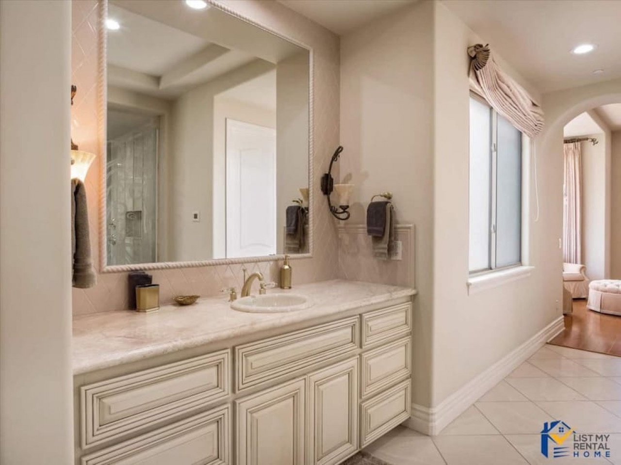 Indulge in your spa-like master bathroom with elegant marble counters, oversized mirror, and luxurious soaking tub by the window.